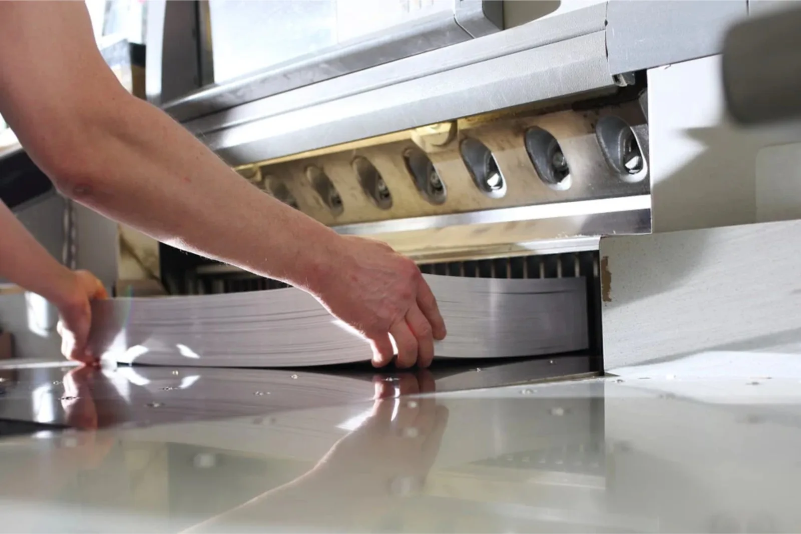 Operator squaring a paper stack in a guillotine cutter